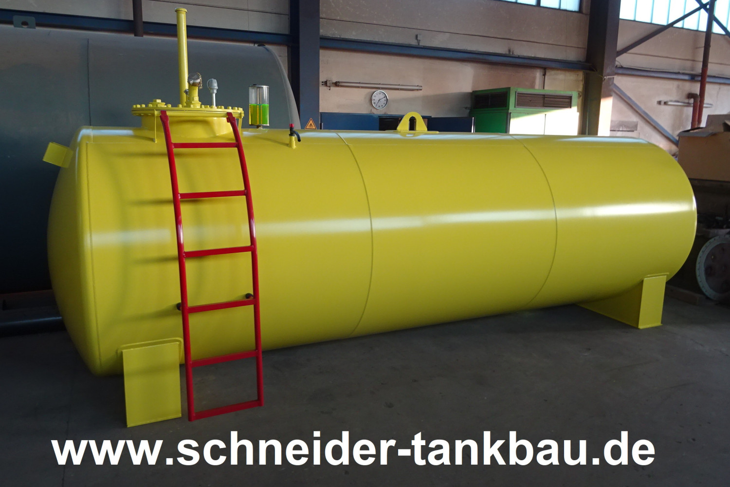 Seitenansicht eines gelben Dieseltanks mit 10.000 Liter Fassungsvermögen und roter Leiter in einer Halle.