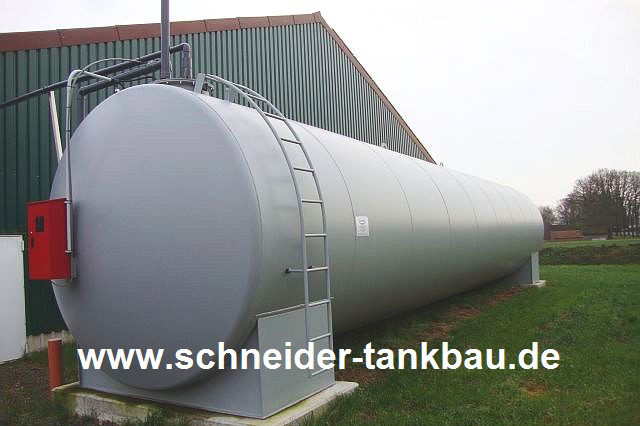 Grauer 20.000 Liter Flüssigdüngerbehälter aufgestellt und montiert auf einem Rasenstück vor einem landwirtschaftlichen Gebäude.