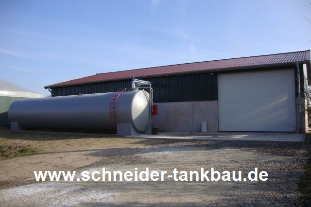 Ansicht eines grauen 100.000 Liter Flüssigdüngertanks vor einem landwirtschaftlichen Gebäude.