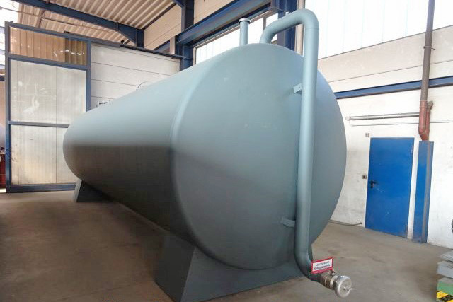 Frontansicht eines grauen 40.000 Liter Löschwassertanks mit Anschlüssen in einer Halle.