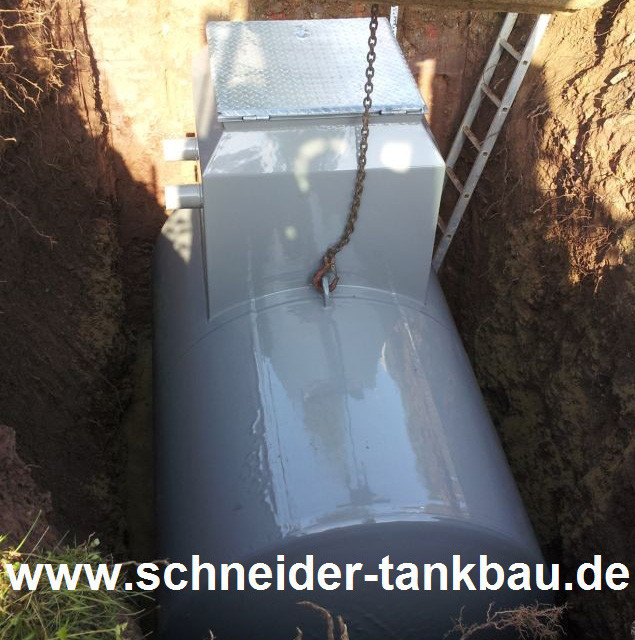 Grauer 5.000 Liter Stahltank mit Domschacht eingelassen in eine Baugrube. 