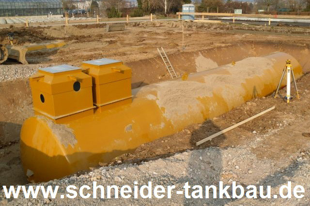 50.000 Liter Erdtank mit zwei Domschächten in Baugrube, teilverfüllt, mit Nivelliergerät
