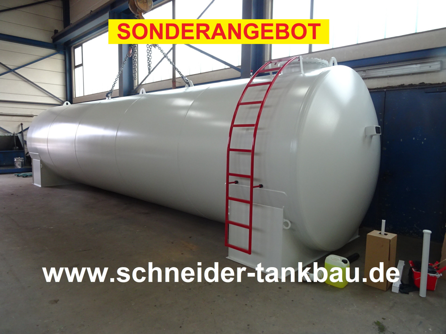 Grauer Heizöltank mit 50.000 Liter Fassungsvermögen und roter Leiter in einer Halle.