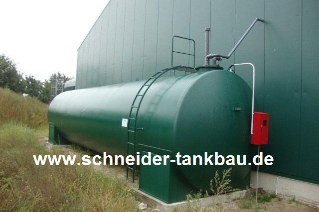 Grünes AHL-Tanklager mit 60.000 Liter Fassungsvermögen an der Außenseite eines Gebäudes. Rohre führen in das Gebäude.