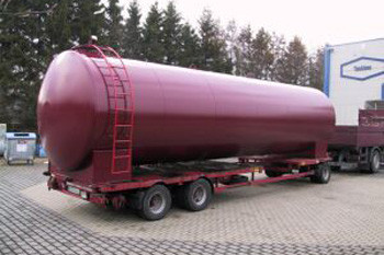Weinroter Heizöltank mit einem Fassungsvolumen von 60.000 Litern zum Transport vorbereitet auf einem Anhänger.