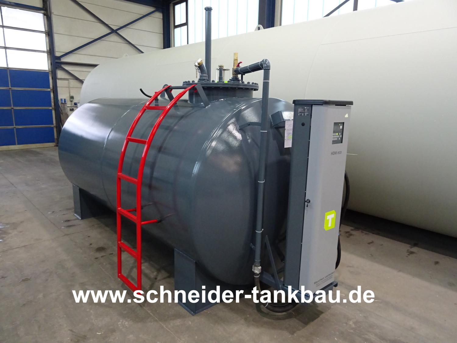Grauer Dieseltank mit 7.000 Liter Fassungsvermögen und montierter Tankvorrichtung in einer Halle.