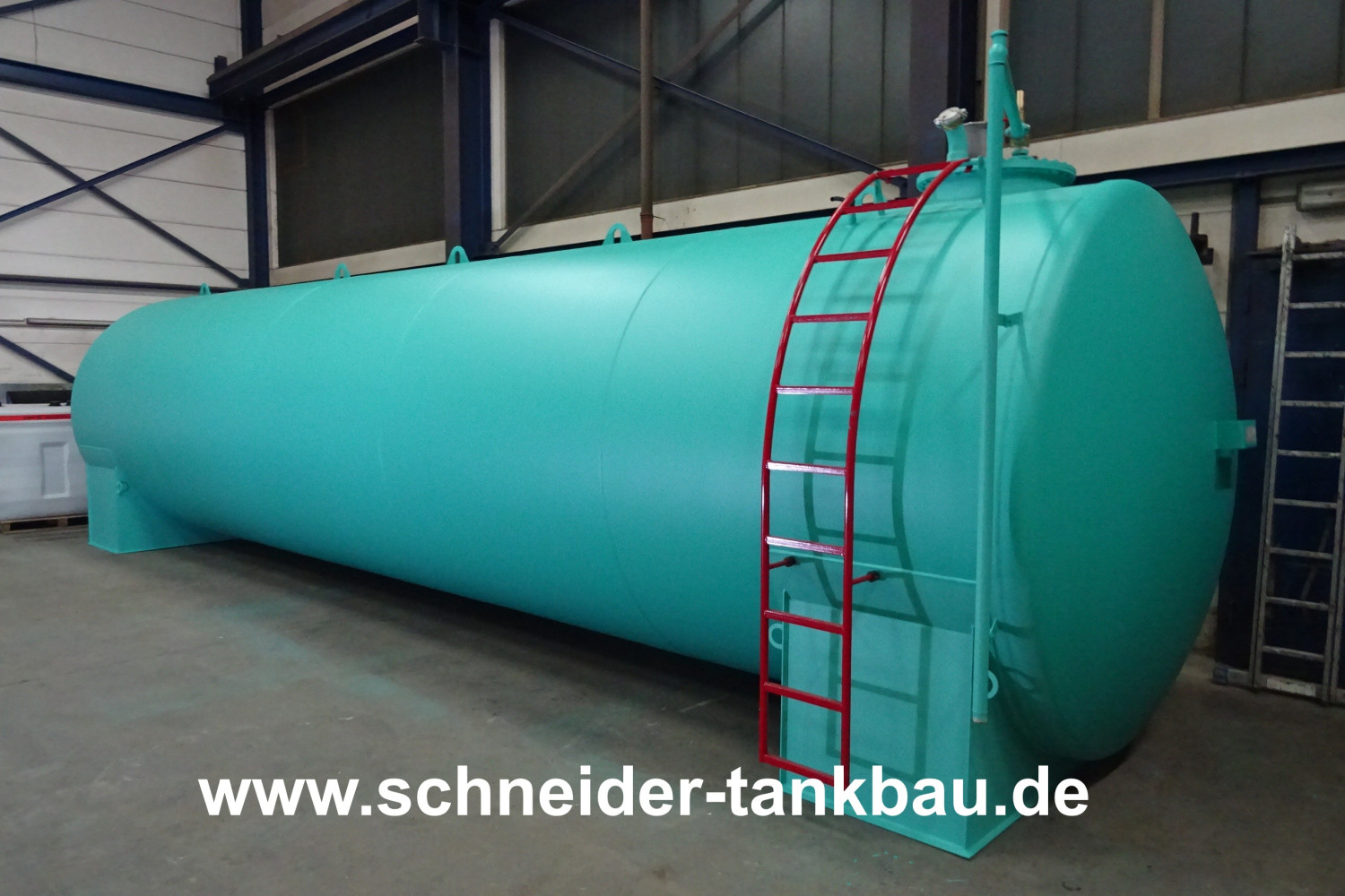 Türkiser Heizöltank mit 40.000 Liter Fassungsvermögen und roter Leiter in einer Halle.